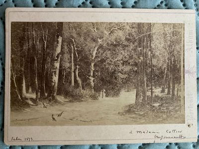 an old photo of a dirt road in a wooded area