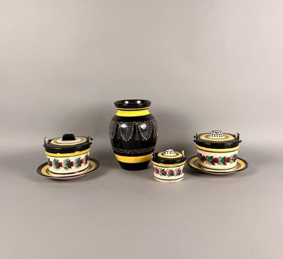un vase noir et jaune ainsi que deux tasses et soucoupes posées sur une table