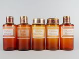 quatre bouteilles contenant un liquide de couleur orange, posées les unes à côté des autres sur une surface blanche