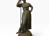 statue en bronze représentant une femme tenant un bâton et debout sur un socle