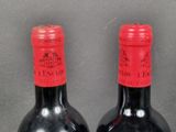 two bottles of red wine sitting next to each other on a table