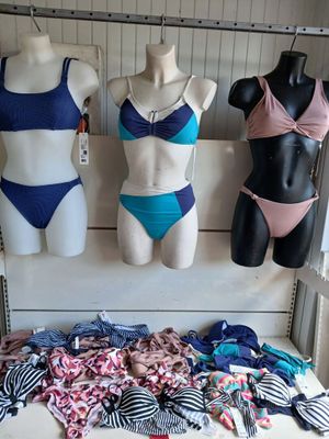 three mannequins are lined up on a shelf in front of a display of swimsuits