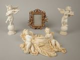 three statues of angels and a picture frame on a table