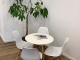a white table with four chairs and a potted plant