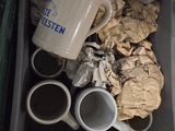 many cups and mugs in a bin on the floor