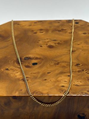 un collier posé sur une boîte en bois, sur fond blanc