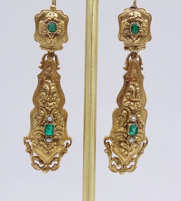 une photo d'une paire de boucles d'oreilles en or serties d'émeraudes