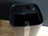 a black trash can sitting on the floor next to a computer mouse