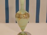 a green vase sitting on a white table with a blue and white striped chair in the background