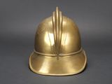 brass plated helmet with feathers on top of it on a gray surface