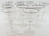 six clear wine glasses are lined up in a row on a white surface
