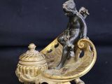 bronze figurine of a boy on a boat with a lid
