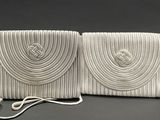 two white purses sitting on top of a table next to each other