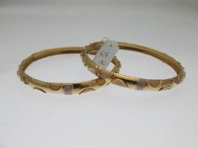 deux bracelets en or ornés de motifs gravés sur un fond blanc