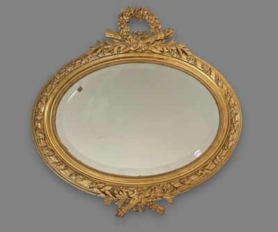 an oval mirror with a gold frame on a gray wall