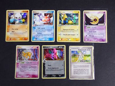 Plusieurs cartes Pokémon sont alignées sur une surface noire