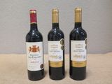 trois bouteilles de vin posées sur une table, l'une à côté de l'autre