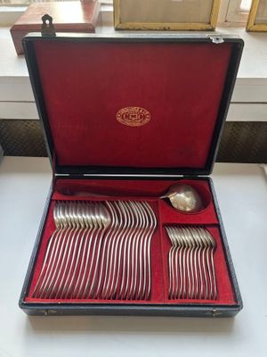 des couverts dans un coffret posé sur une table, avec une fenêtre en arrière-plan