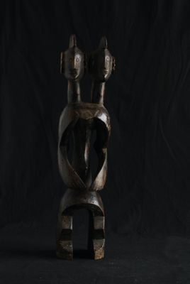 une sculpture en bois représentant un homme à deux cornes sur fond noir