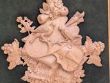 wooden carving of a coat of arms with flowers and a bird