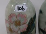 two vases with flowers painted on them sitting on a table