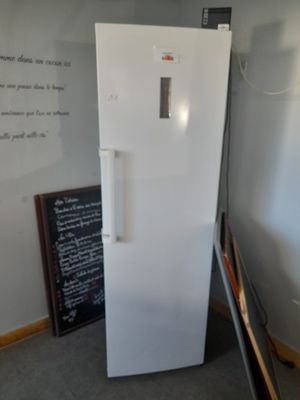 un réfrigérateur blanc dans une pièce où se trouve un tableau noir accroché au mur