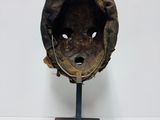 an old baseball helmet on a stand on a white surface