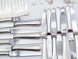 a lot of silverware on a table with a knife, fork, spoon, and spoon rest