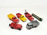cinq camions miniatures et un bus posés sur une surface blanche