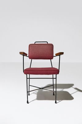 une chaise rouge posée sur un sol blanc, près d'un mur blanc