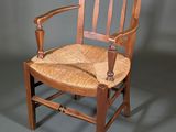 an image of a wooden chair with a wicker seat on a gray floor