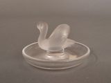 a glass swan sitting on top of a glass ashtray
