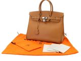 un sac en papier brun posé sur une couverture orange, à côté d'un portefeuille
