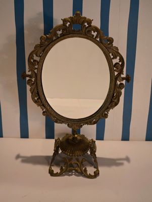 a mirror on a stand with a blue and white striped wall behind it