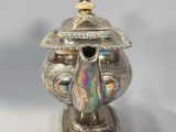 an image of a silver teapot with a lid on a white surface