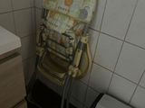 a high chair in the corner of a bathroom next to a trash can