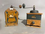 two old fashioned coffee grinders sitting on a table