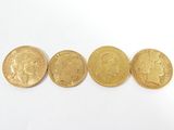 quatre pièces d'or sont alignées sur une surface blanche