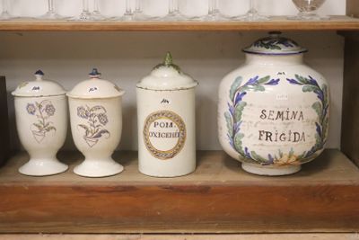 trois vases posés sur une étagère, avec des verres à vin en arrière-plan