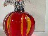 un flacon de parfum en verre rouge surmonté d'un oiseau