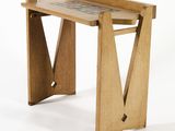 a small wooden table with a tile top on it