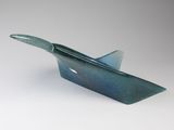 blue and green glass bowl with a curved handle on a white surface