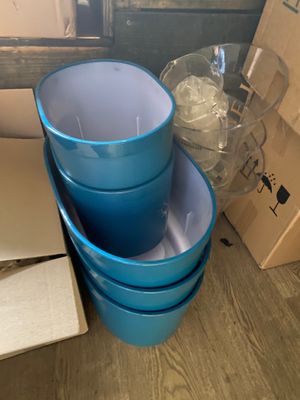 three blue plastic buckets stacked on top of each other on a wooden floor