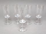 four empty wine glasses are lined up on a white surface