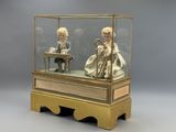 deux poupées posées dans une vitrine posée sur une table