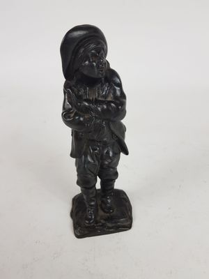 figurine représentant un homme portant un chapeau et un sac sur le dos
