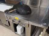 un plan de travail en acier inoxydable sur lequel est posée une poêle, dans une cuisine professionnelle