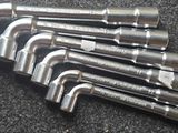 six serres-tubes en acier inoxydable sont alignées sur une surface noire
