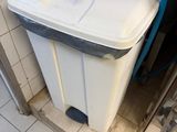 a trash can in the corner of a bathroom