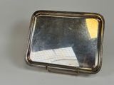 un petit miroir posé sur une table, à côté d'une feuille de papier